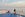 Person standing against the railing on the outer deck of a cruise ship looking at the ocean