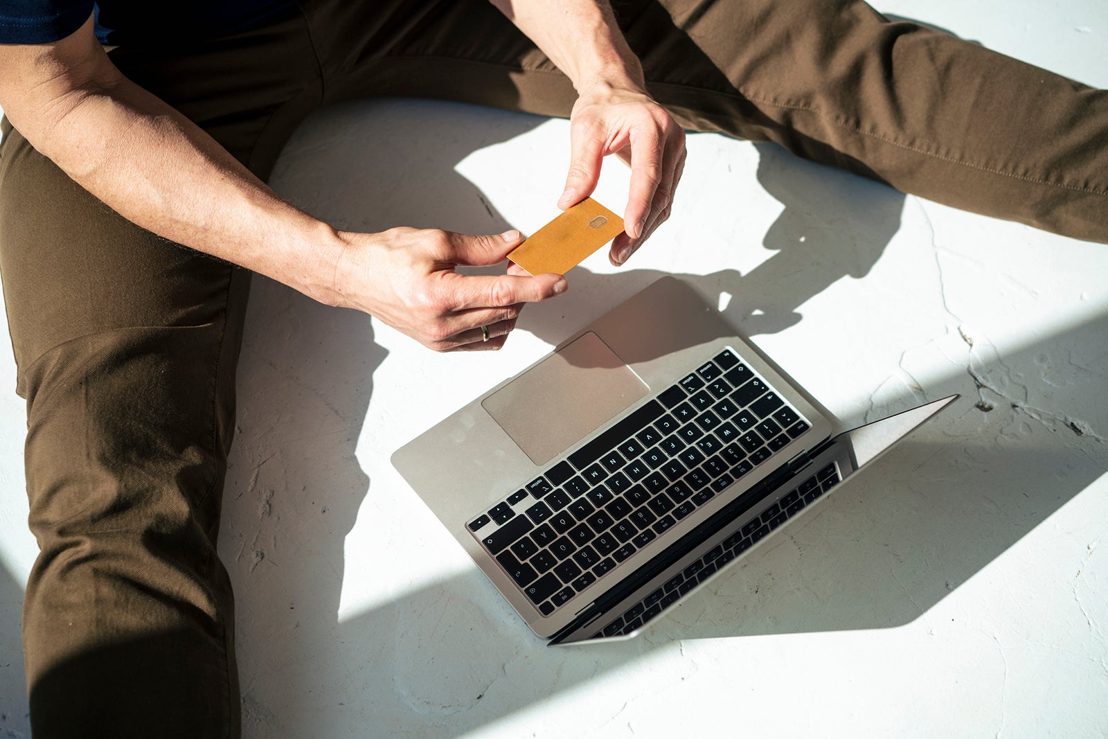 Businessman doing online shopping sitting on floor with credit card and laptop
